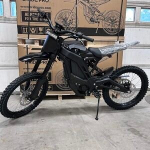 Black E-Ride Pro electric dirt bike in front of packaging box in a garage